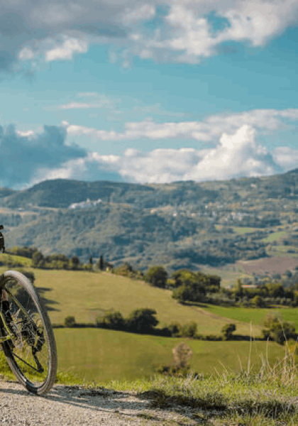 Ciclista su una collina, guarda il paesaggio.
