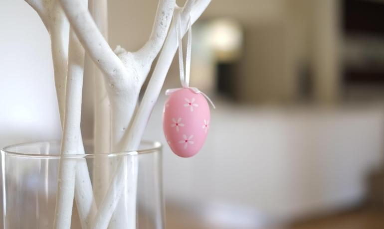 Uovo rosa decorativo appeso a un ramo bianco.