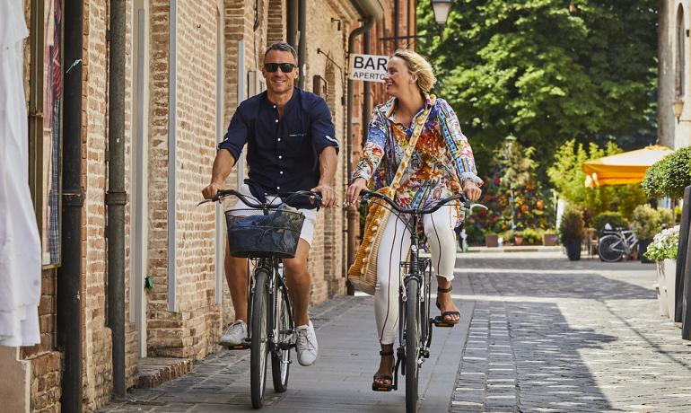 Coppia felice in bicicletta in una strada di città storica.