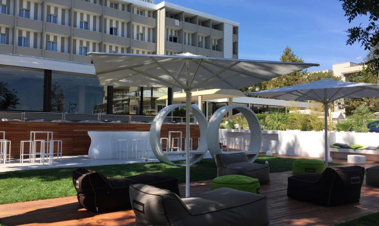 Hotel moderno con giardino, sedie a sdraio e ombrelloni.