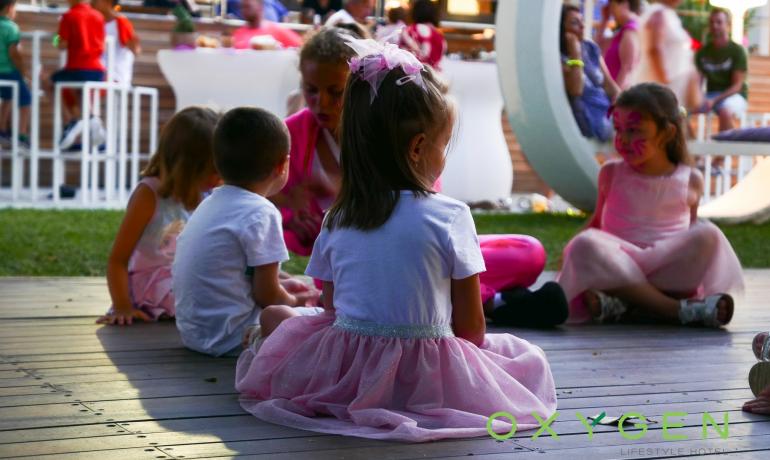 Kinder sitzen auf dem Boden bei einer Outdoor-Veranstaltung.