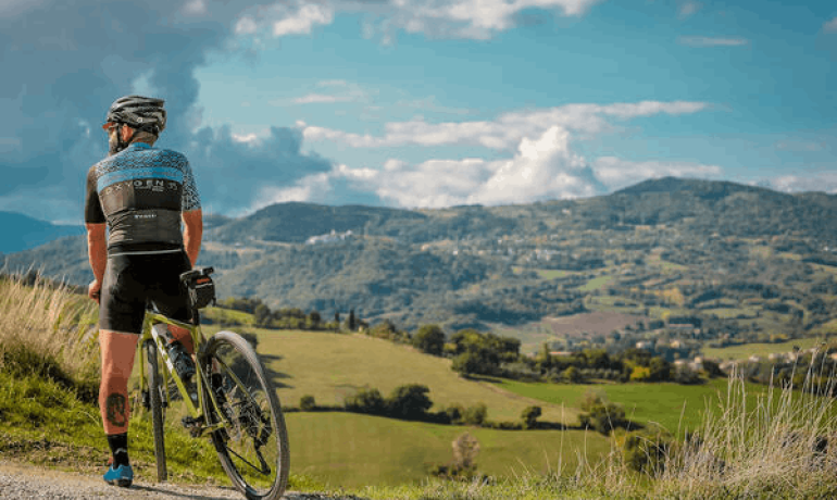 Ciclista su una collina, guarda il paesaggio.