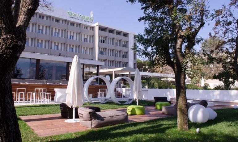 Hotel moderno con giardino, arredi eleganti e area relax.