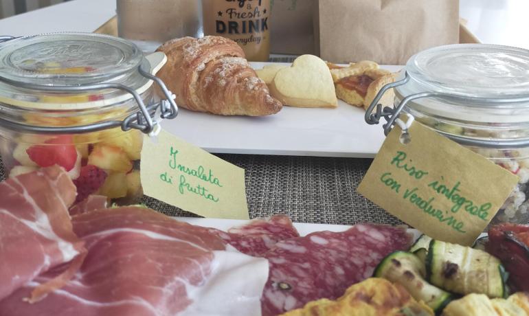 Colazione con salumi, insalata di frutta, pane e bevande fresche.
