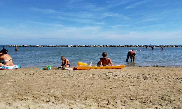 Spiaggia con persone che si rilassano e giocano vicino al mare.