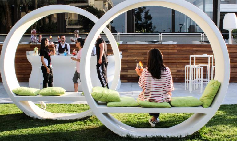 Persone si rilassano in un'area lounge all'aperto con sedute circolari.