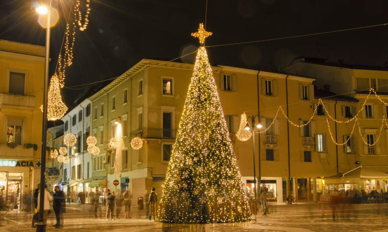 Albero di Natale illuminato in piazza con decorazioni festive.