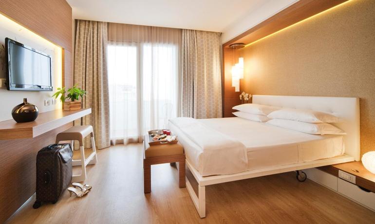 Camera moderna con letto matrimoniale, TV a schermo piatto e decorazioni eleganti.