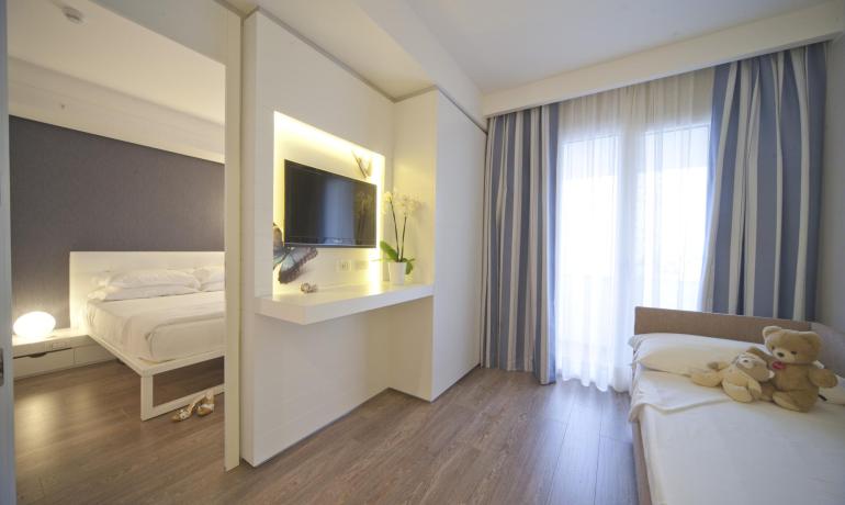 Camera luminosa, elegante con due letti, TV e peluche su un letto.