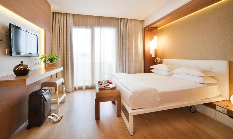 Camera moderna con letto matrimoniale, TV e arredamento elegante.