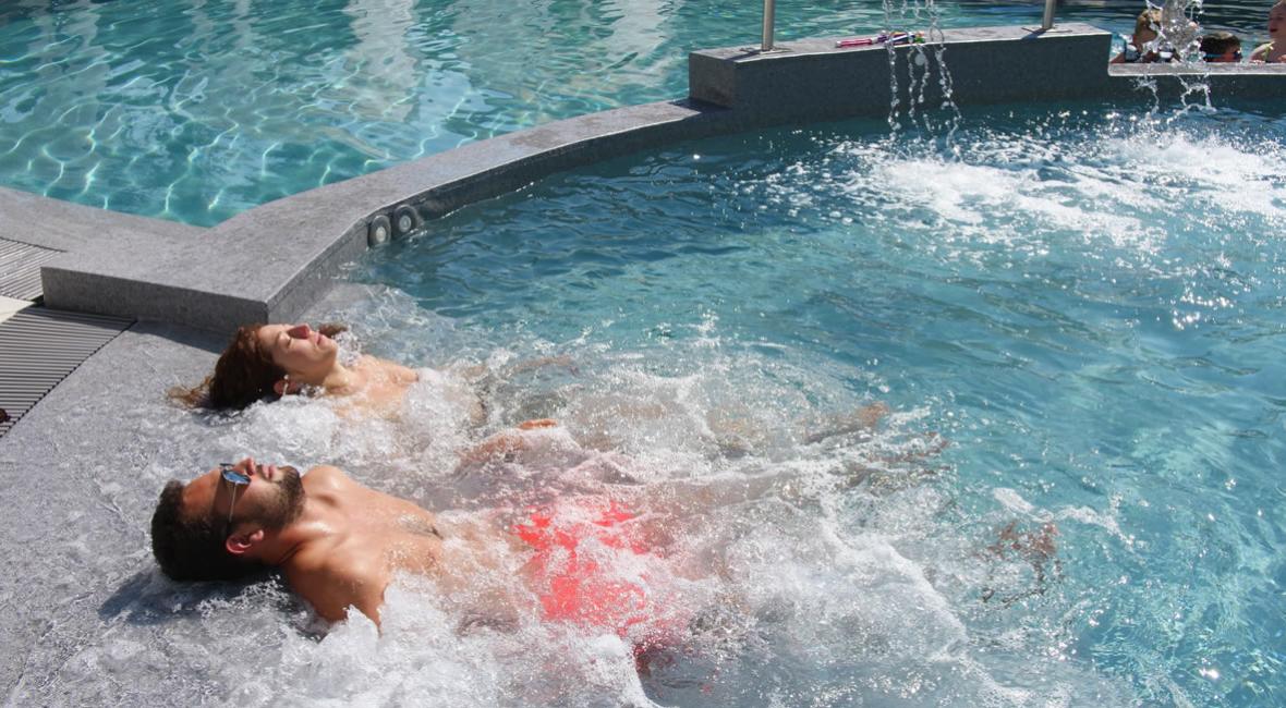 Due persone si rilassano in una piscina con getti d'acqua.