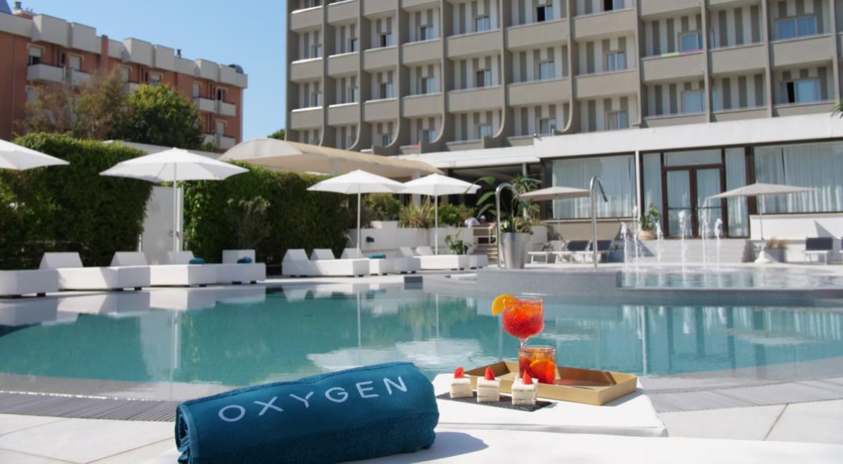Piscina di un hotel con lettini, ombrelloni e bevande rinfrescanti.