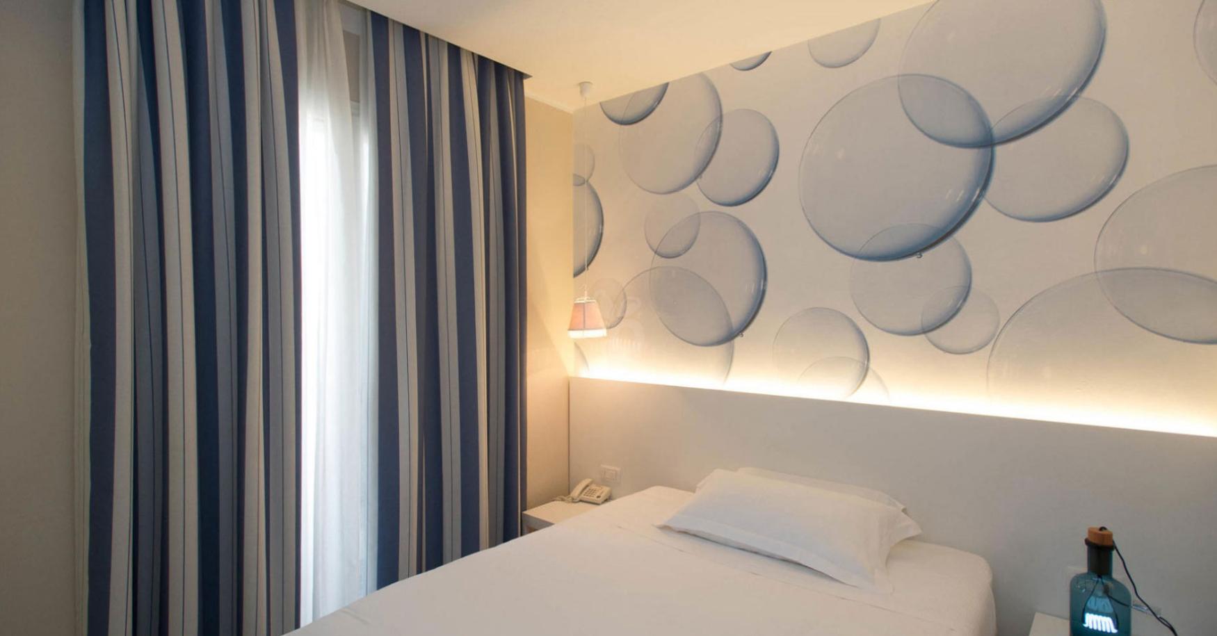 Bedroom with decorated wall and blue and white striped curtains.