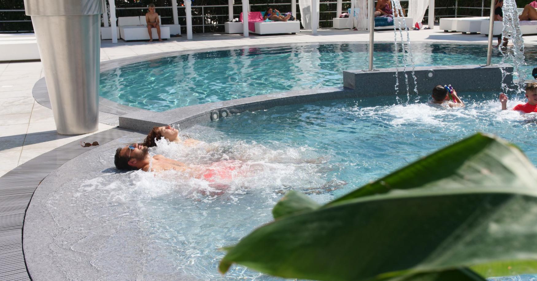 Persone che si rilassano in una piscina con getti d'acqua.