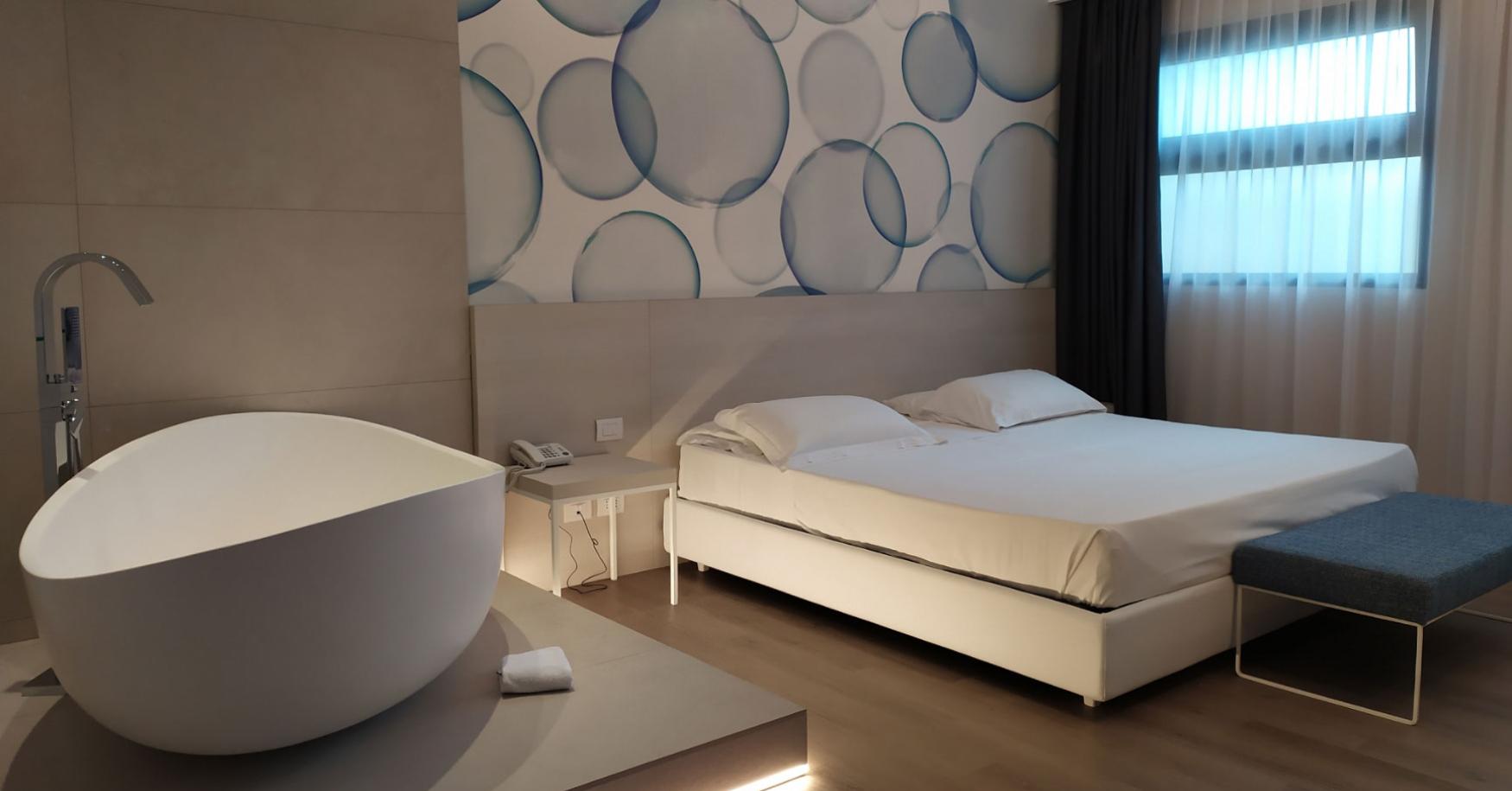 Camera moderna con letto, vasca da bagno e decorazioni murali circolari.