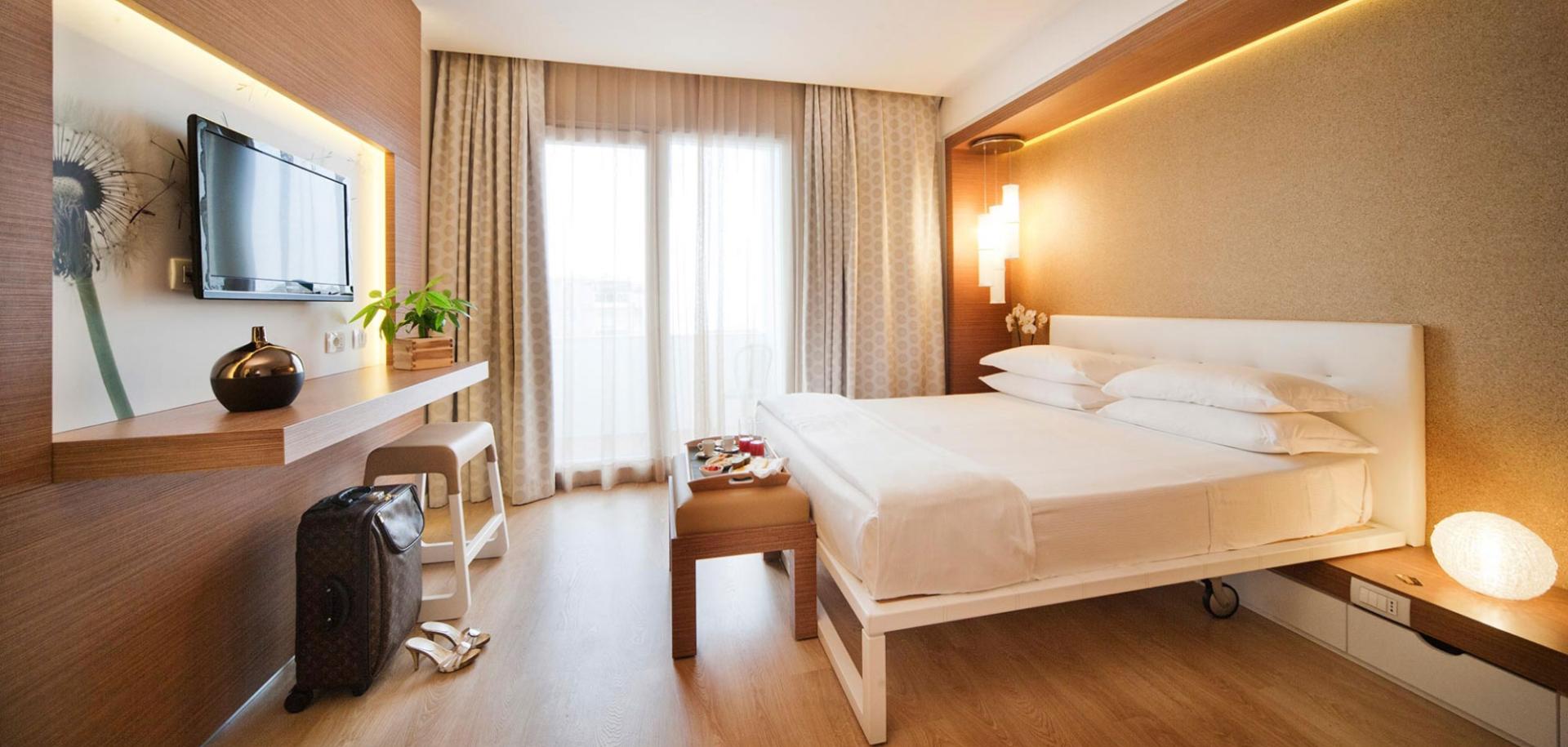 Elegante camera d'hotel con letto matrimoniale, TV e vista sulla terrazza.