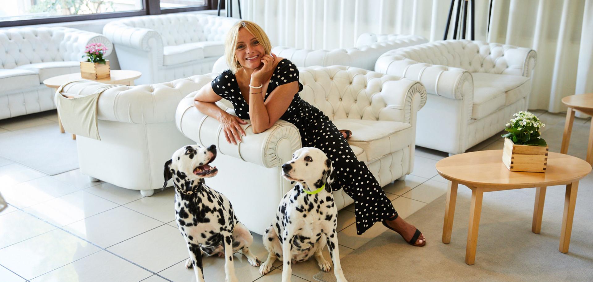 Donna con due dalmata in un elegante salotto bianco.