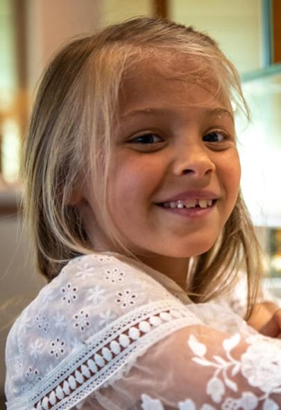 Bambina sorridente davanti a un buffet di cibo colorato.