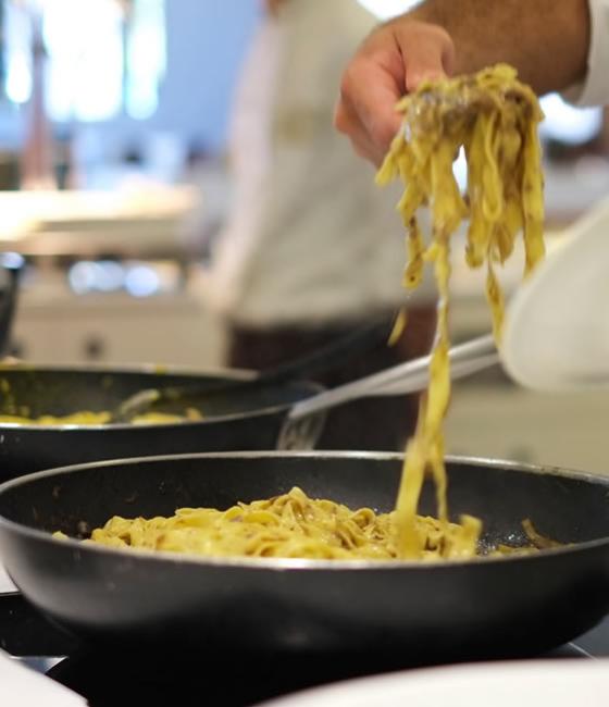 Koch serviert Tagliatelle aus der Pfanne, Gourmet-Küche.