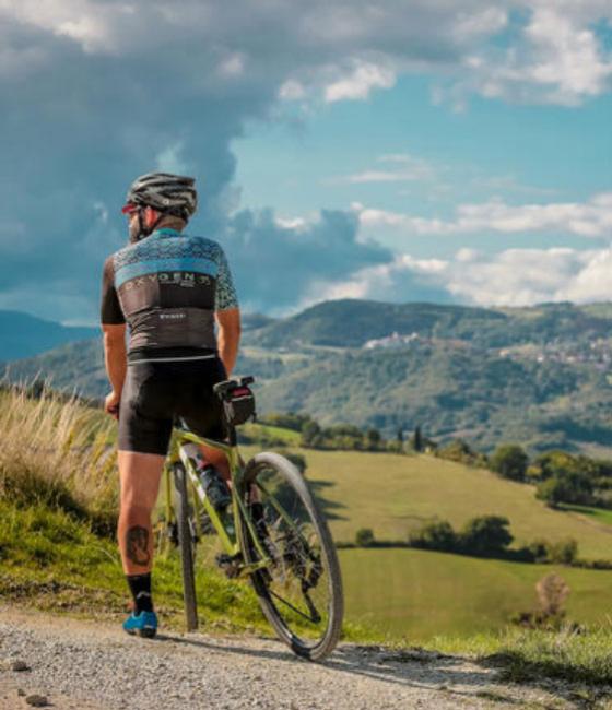 Radfahrer auf einem Hügel mit Panoramablick, bewölkter Himmel.