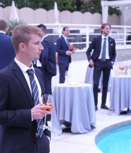 Uomini in abiti eleganti con cocktail vicino a una piscina.
