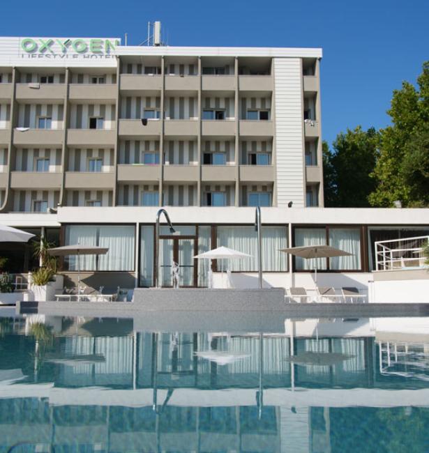 Hotel moderno con piscina e balconi, cielo sereno.